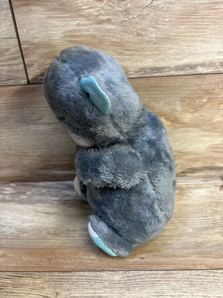 Gray plush elephant toy with blue ear and foot accents on wooden floor