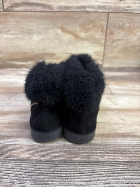 Rear view of Self Esteem City Girl faux-fur boots in black showcasing plush faux-fur cuffs on a wood-look floor