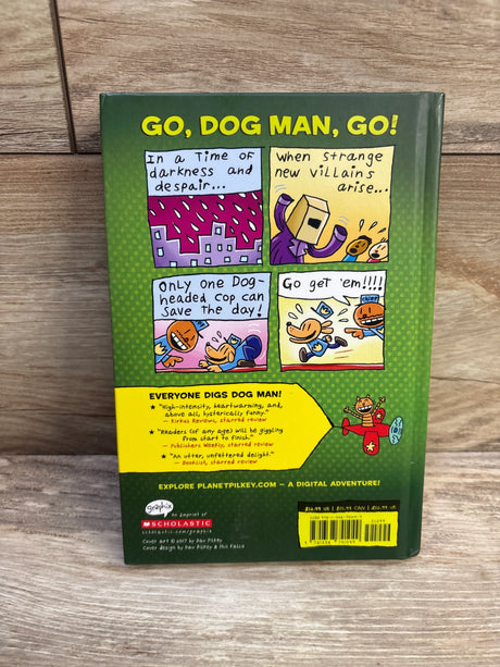 Back view of Dog Man Unleashed #2 hardcover book showing GO, DOG MAN, GO! headline and comic-strip back cover on wooden surface