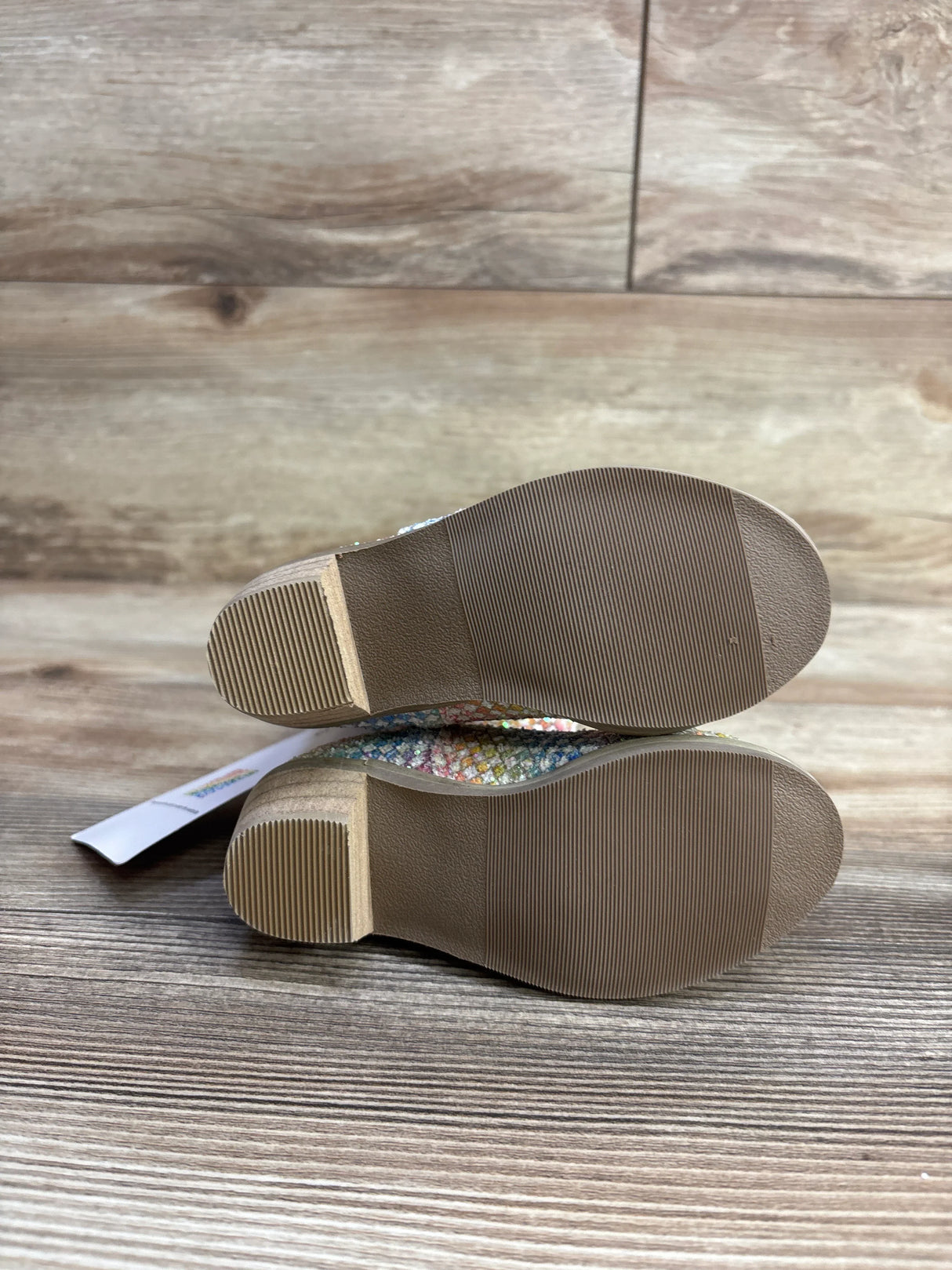 Bottom view of children's colorful glittery shoes on wooden floor, resale kids footwear