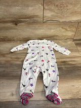 White baby onesie with colorful sneaker and star print, footed design on wood floor