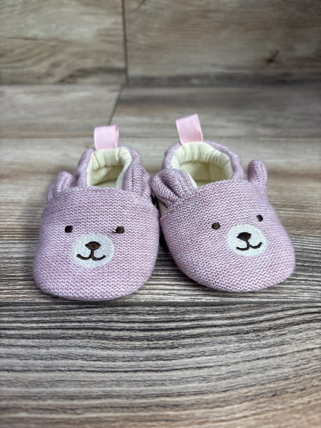 Front view of pink Bearpaw knit bear booties with bear faces, ears, pull tabs, and cream lining on a wood background