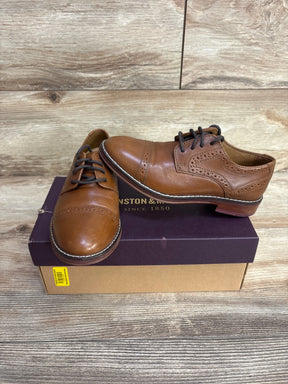 Brown leather dress shoes with black laces on a brown and purple shoebox against wood background