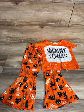 Orange Halloween kids pajamas set with ghosts, pumpkins, 'Wickedly Cute' text, and 'BOO!' print on wood floor