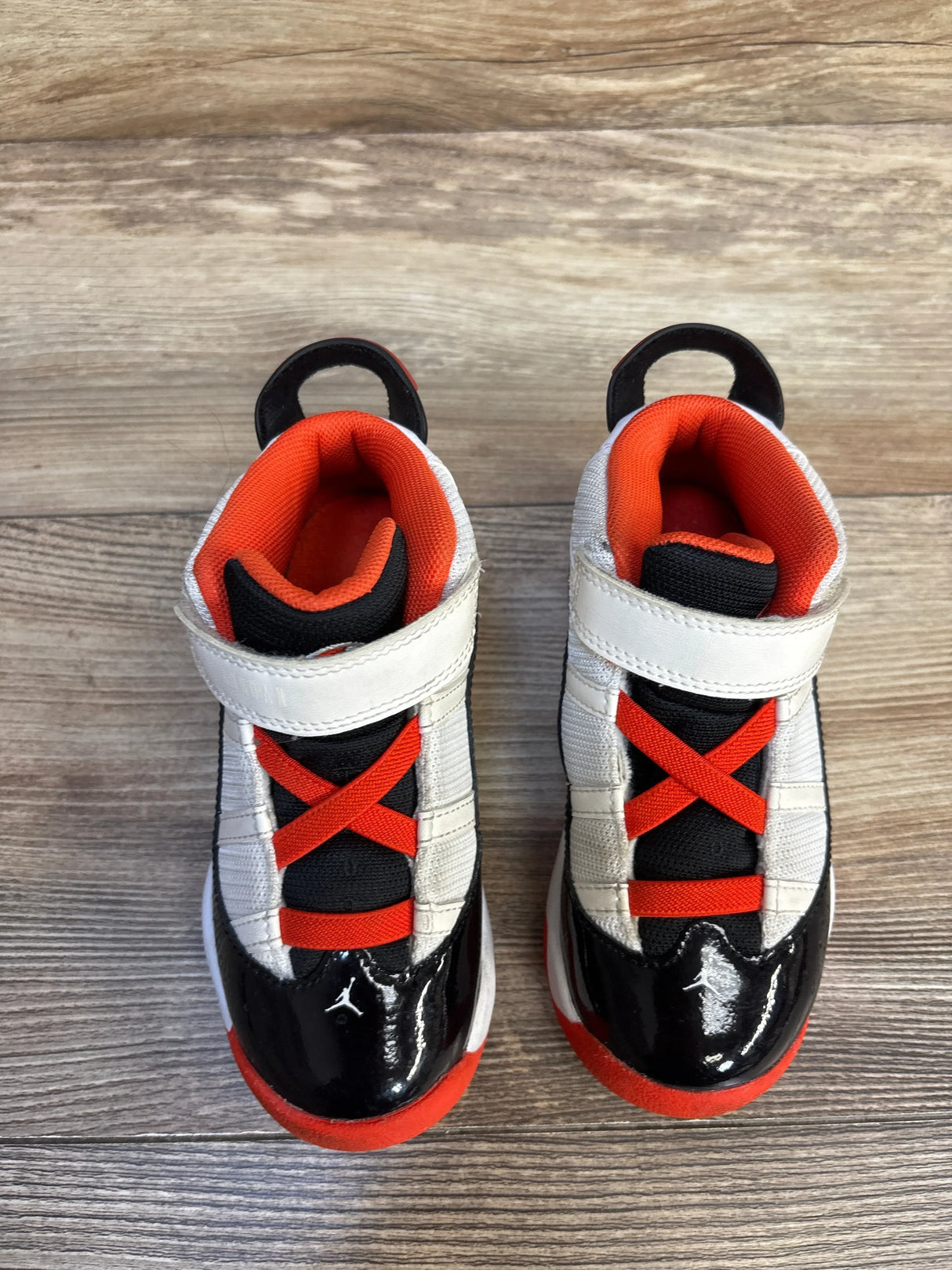 Kids' black and orange high-top sneakers with velcro straps on wood floor