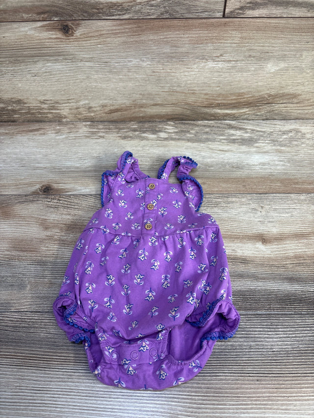 Top view of Carter's purple floral bubble romper, 3M, with ruffle straps, front wood buttons and snap crotch on wood floor