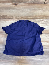Back view of a short sleeve navy blue kids shirt on wood floor