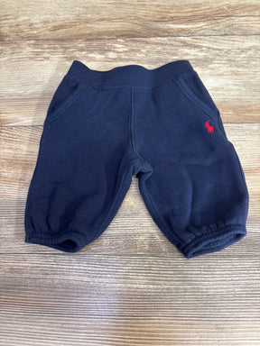 Navy blue baby jogger pants with elastic waistband and red logo on wooden background
