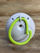 White plastic baby gear accessory with green hook on wood background