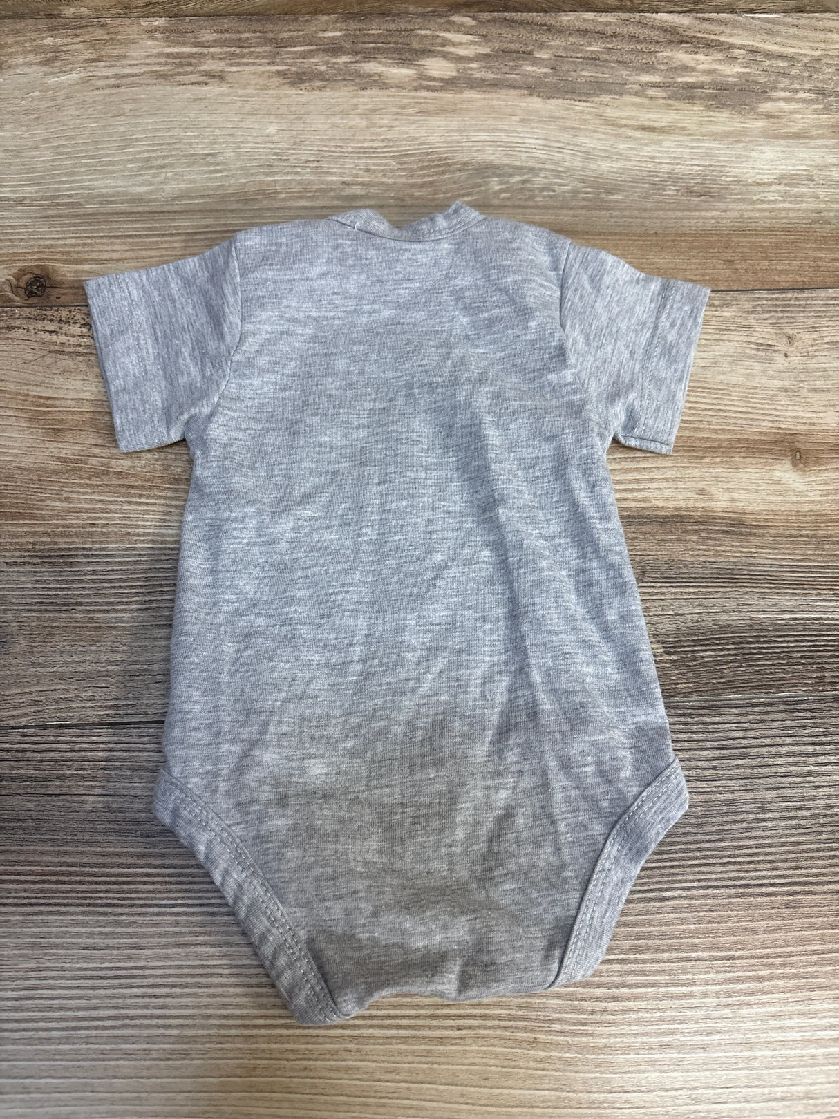 Gray short sleeve baby bodysuit on wood background, gently used kids clothing