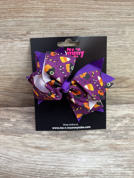 Large purple Halloween print hair bow with pumpkins and candy on a black display card