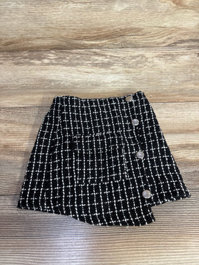 Black and white plaid tweed mini skirt with buttons, displayed on wooden background