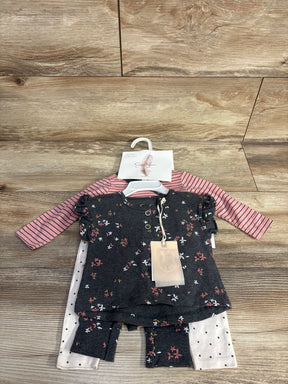 Baby girl clothing set with floral top, striped pink shirt, and polka dot pants on wood background
