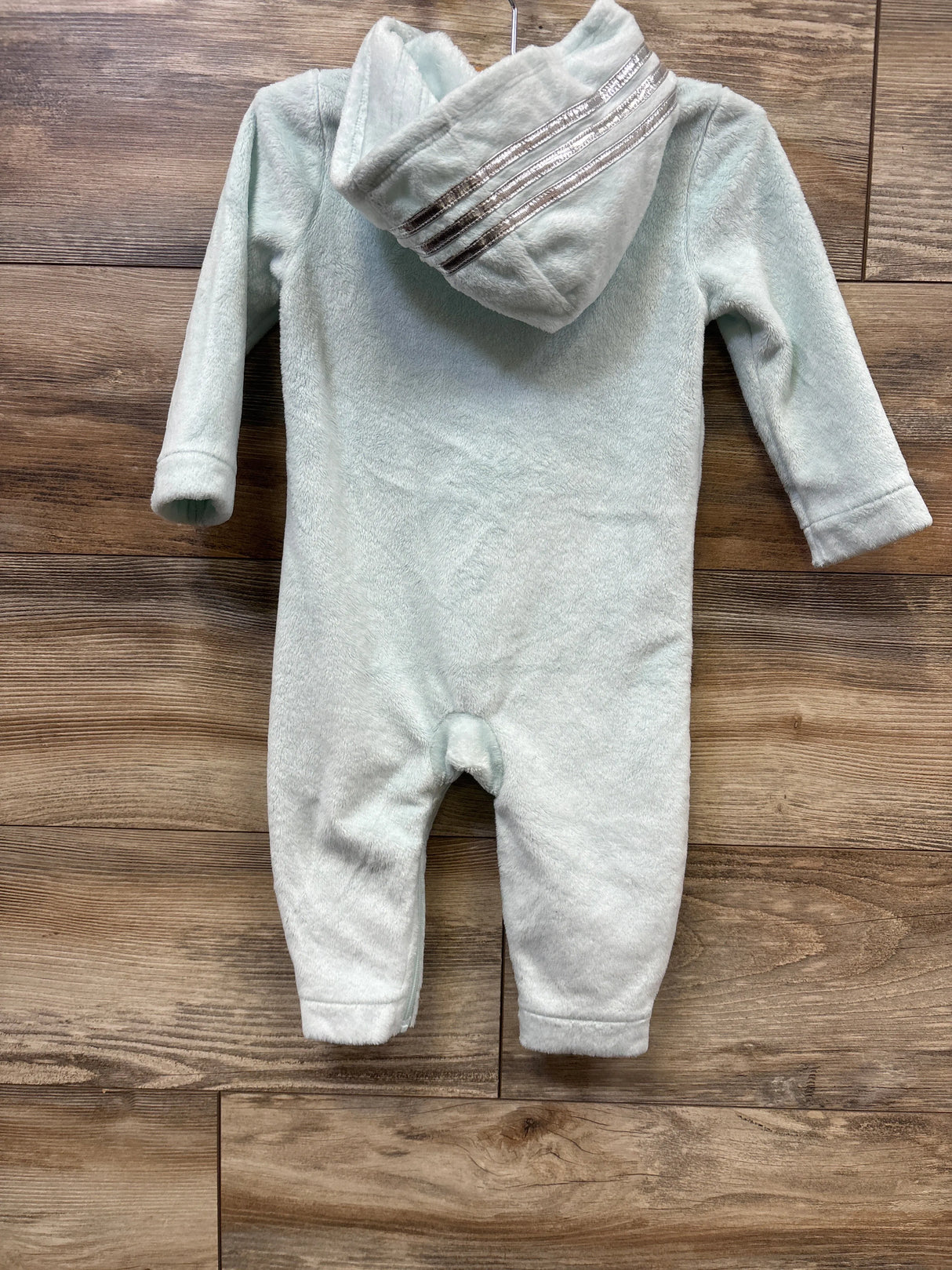 Soft light blue fleece baby onesie with hood and metallic silver stripes, laid flat on wooden floor