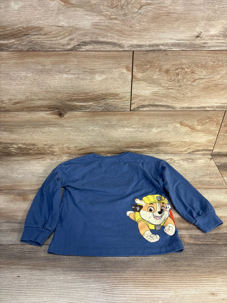 Blue long sleeve toddler shirt with cartoon puppy graphic on back, laid on wood floor