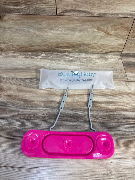 Top-down view of Busy Baby mini mat toy straps in pink showing two gray adjustable straps and three pink suction cups on a wood floor