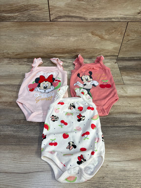 Top-down view of three Disney Baby Minnie Mouse infant bodysuits showcasing front character prints and ruffle shoulder straps on light wood background