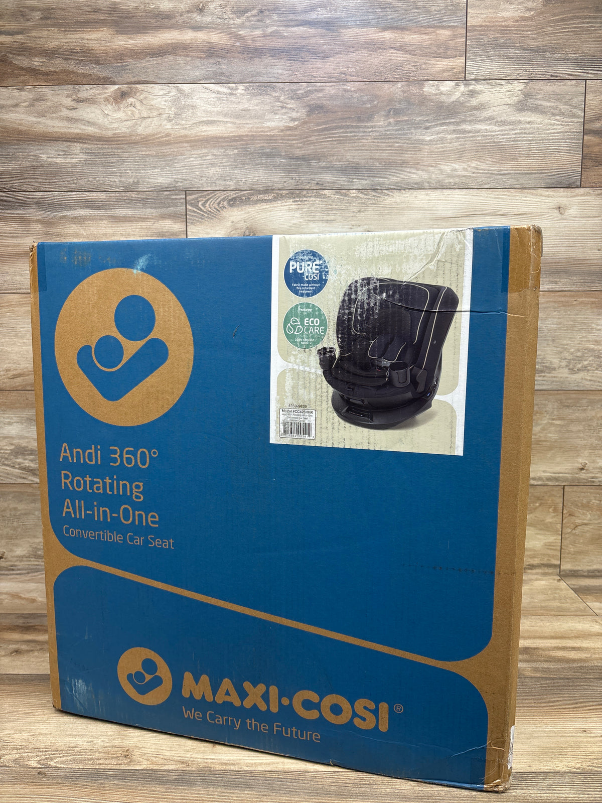 Front view of boxed Maxi-Cosi Andi convertible car seat showcasing 360 rotating all-in-one design on wood flooring
