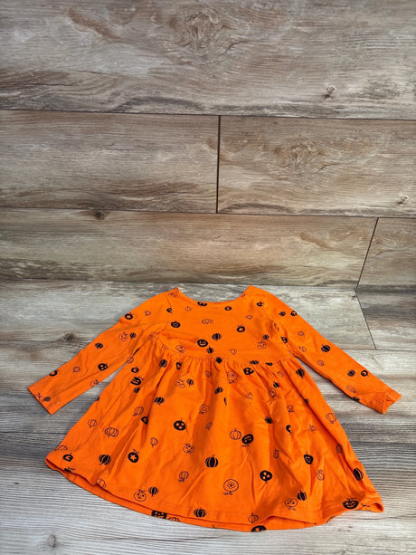 Flat lay of Cat & Jack toddler long-sleeve Halloween dress showcasing orange fabric with black pumpkin print, size 3T on wood background