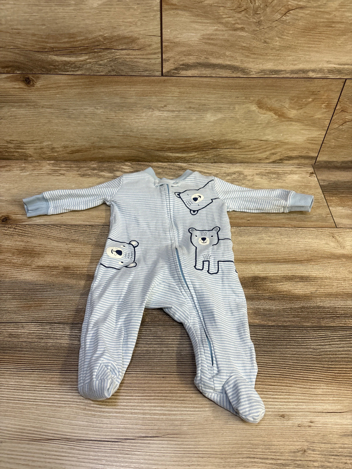 Top view of Carters ribbed sleeper in blue, size 3 months, with bear designs and front zipper on wood flooring
