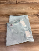 Light blue baby swaddle blanket with 'The Ollie' label, soft fabric and Velcro straps, on wood floor