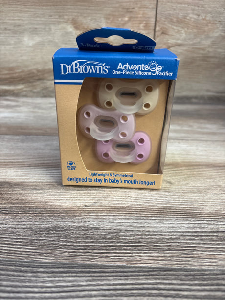 Front view of Dr. Brown’s one-piece silicone pacifier 3-pack (0–6m) showing three pastel pacifiers in box on wood surface