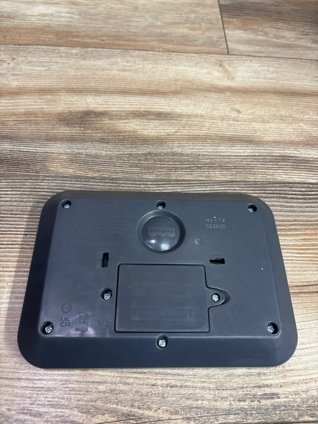 Back view of Fisher Price Laugh & Learn Smart Stages Tablet showcasing battery compartment with wood-grain background