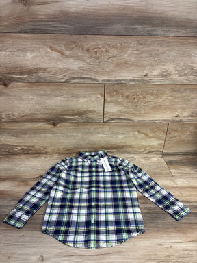 Button-up kids plaid shirt with navy, white, and green pattern on wooden floor background