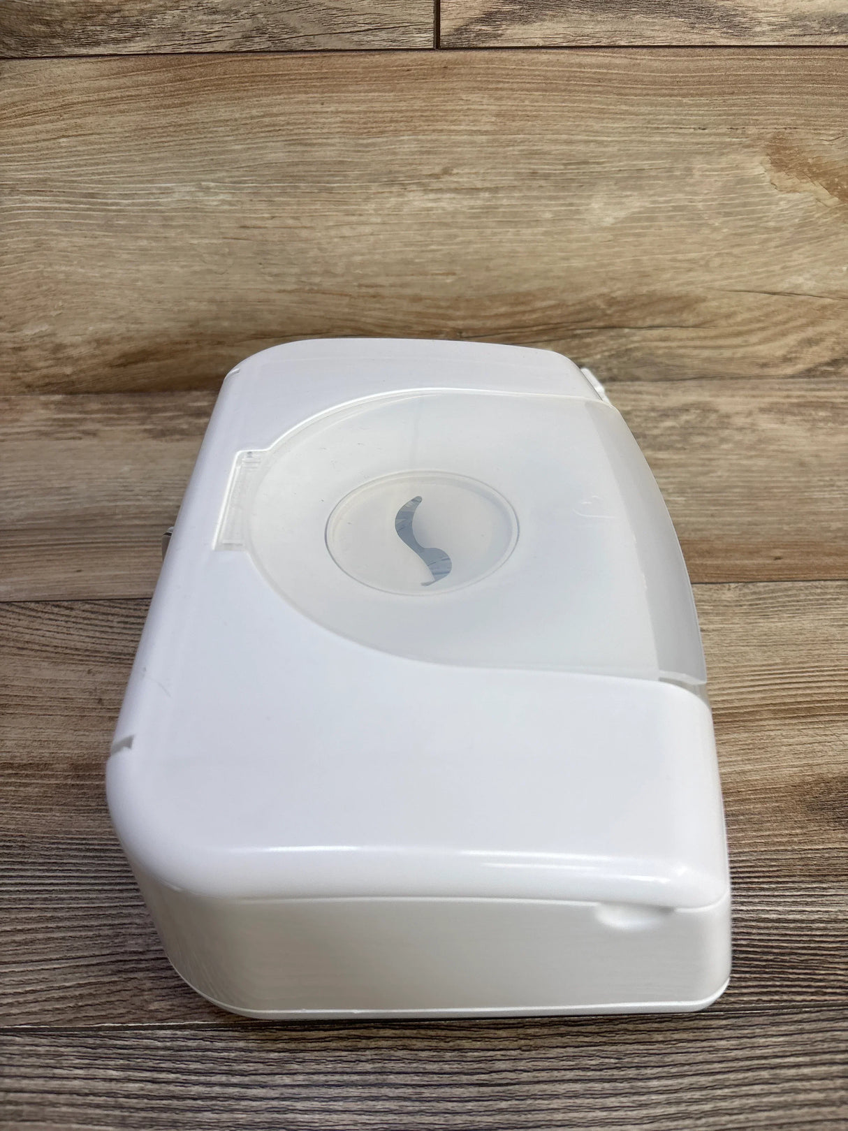 Angled top view of Munchkin Bright & Warm wipe warmer showing closed translucent lid and front tab on wood background