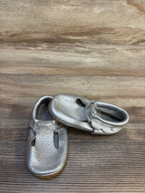 Silver baby shoes with soft leather finish on wood background, gently used kids footwear