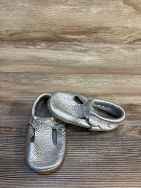 Silver baby shoes with soft leather finish on wood background, gently used kids footwear