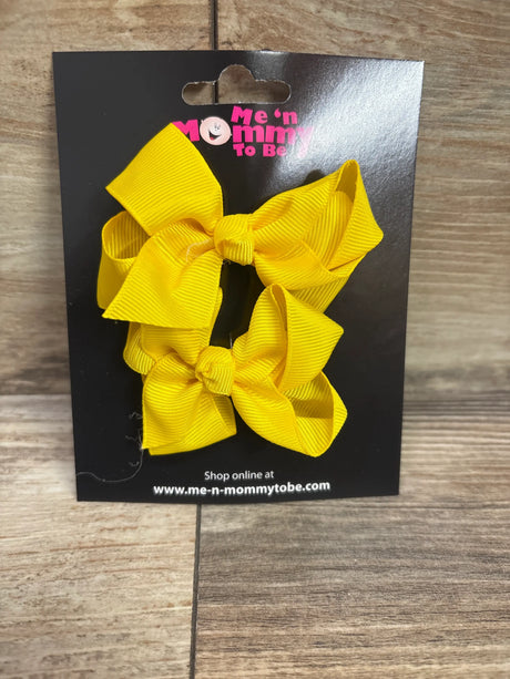 Front view of a yellow two-pack of hair bows showcasing ribbed ribbon loops on a black display card with a wood background