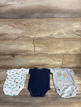 Flat lay of 3-pack Hudson Baby bodysuits size 3-6M showing dinosaur prints and navy bodysuit on wood background