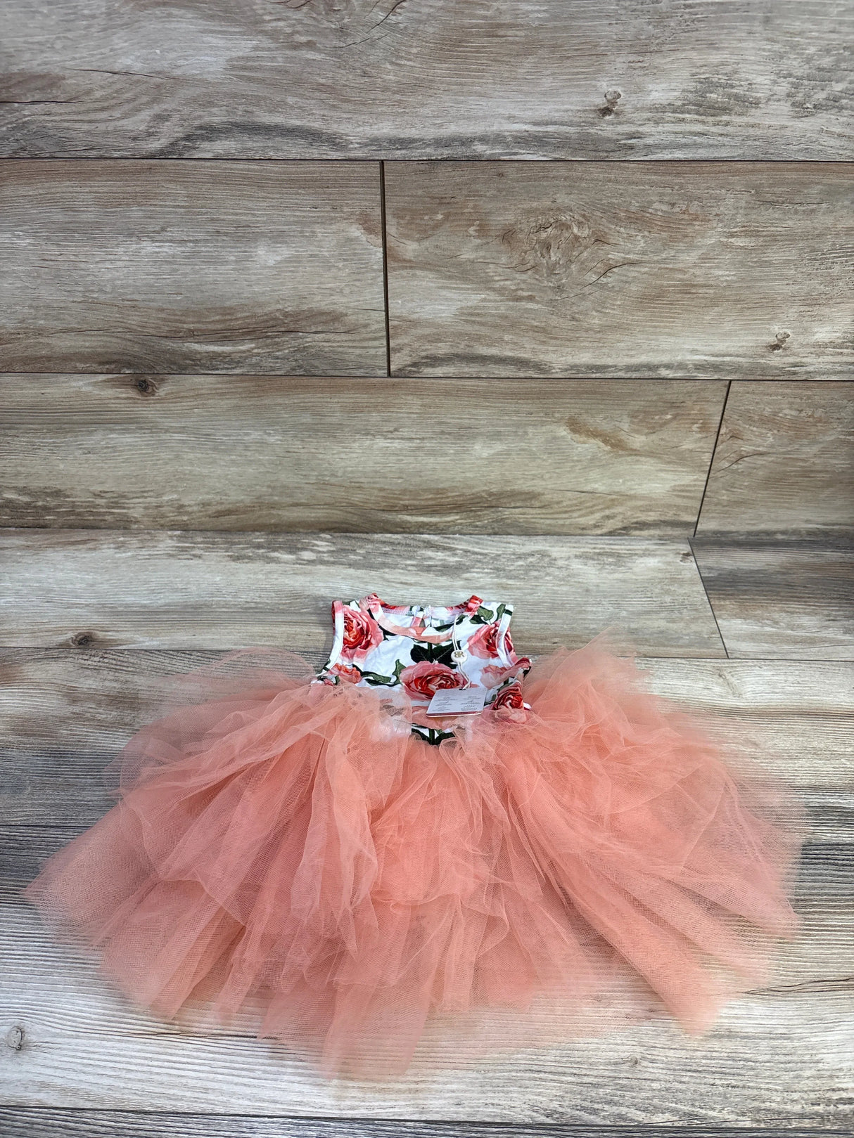 Flat lay of 12–18M Bums and Roses sleeveless dress showing floral bodice and layered peach tulle tutu on light wood floor