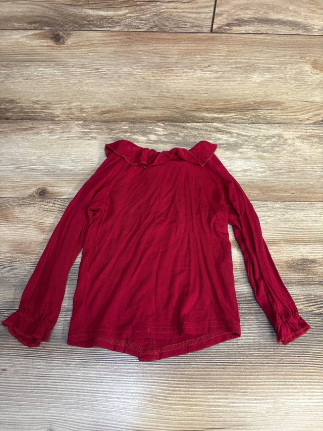 Red long sleeve girls shirt with ruffle collar and cuffs on wood background