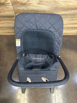 Blue fabric baby bouncer seat with safety bar and mesh backrest on wood floor