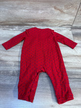 Red baby romper with blue heart print, long sleeves, laid flat on wood background