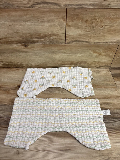 Two white muslin burp cloth bibs with a colorful pattern on a wooden background