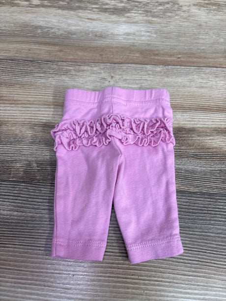 Front view of pink Child of Mine baby pants in preemie size showcasing a ruffled waistband on a wood surface