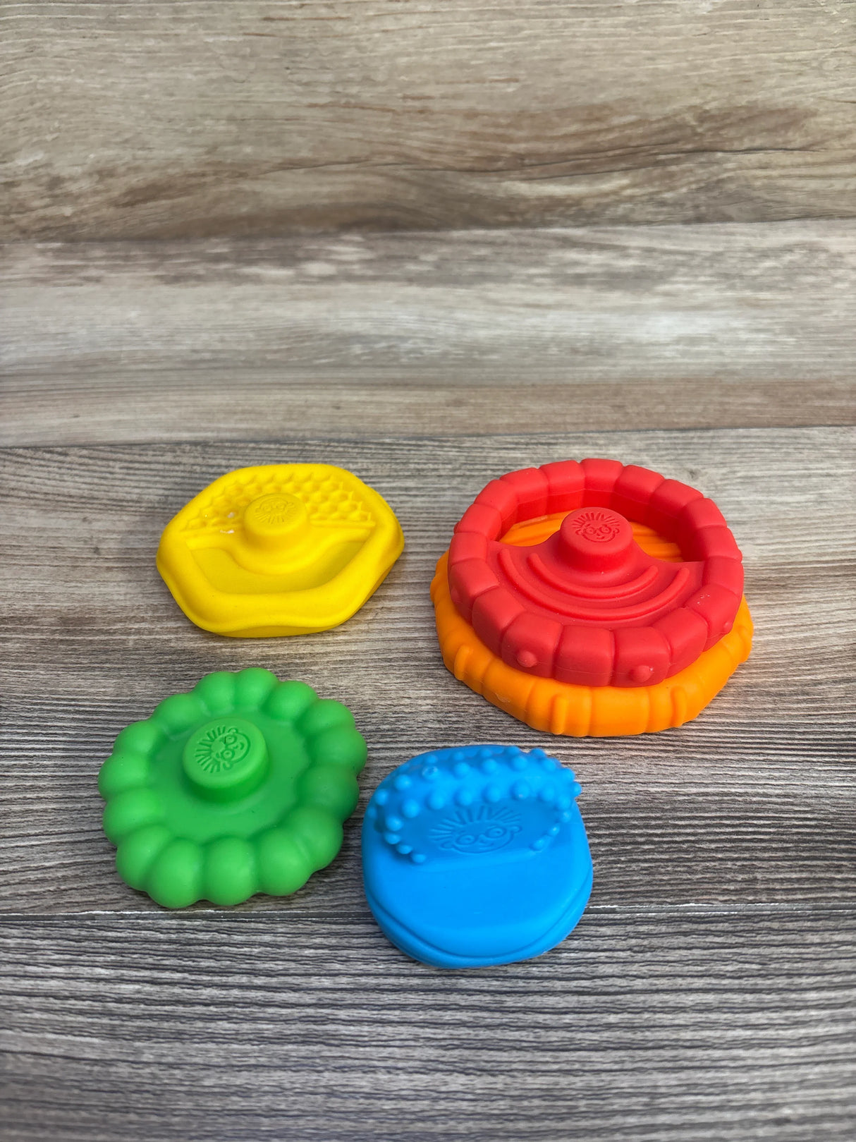 Top view of Baby Einstein 5-piece stacking teethers showing colorful silicone textured pieces on wood background