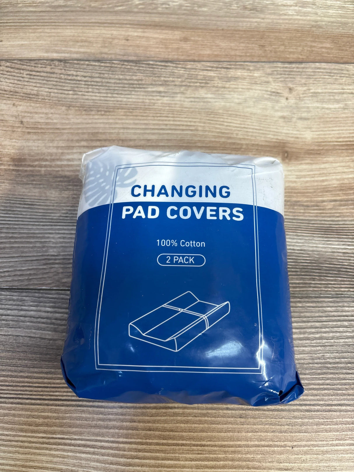 Pack of 2 cotton changing pad covers in blue packaging on wood surface