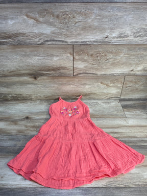 Pink sleeveless toddler dress with floral embroidery on wood background