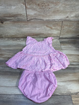Flat-lay of Carter's pink floral dress with matching bloomers, flutter sleeves and elastic waist on wood floor