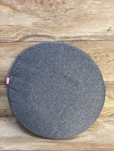 Top-down view of Frida Mom donut pillow showing heather-gray fabric cover and pink Frida tag on wood background