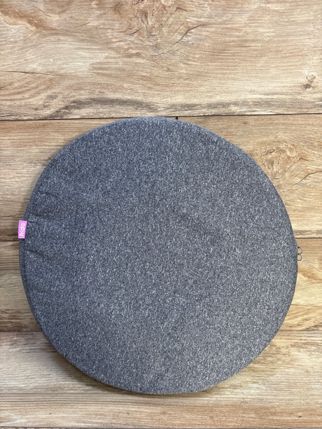 Top-down view of Frida Mom donut pillow showing heather-gray fabric cover and pink Frida tag on wood background