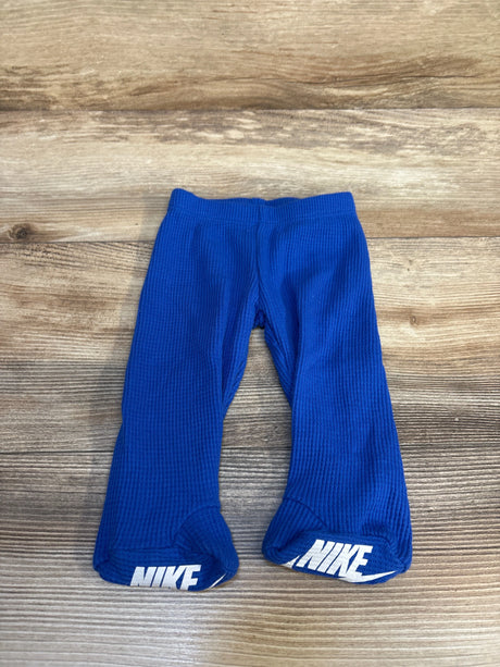 Blue baby Nike footed pants with logo on feet, laid flat on wooden background