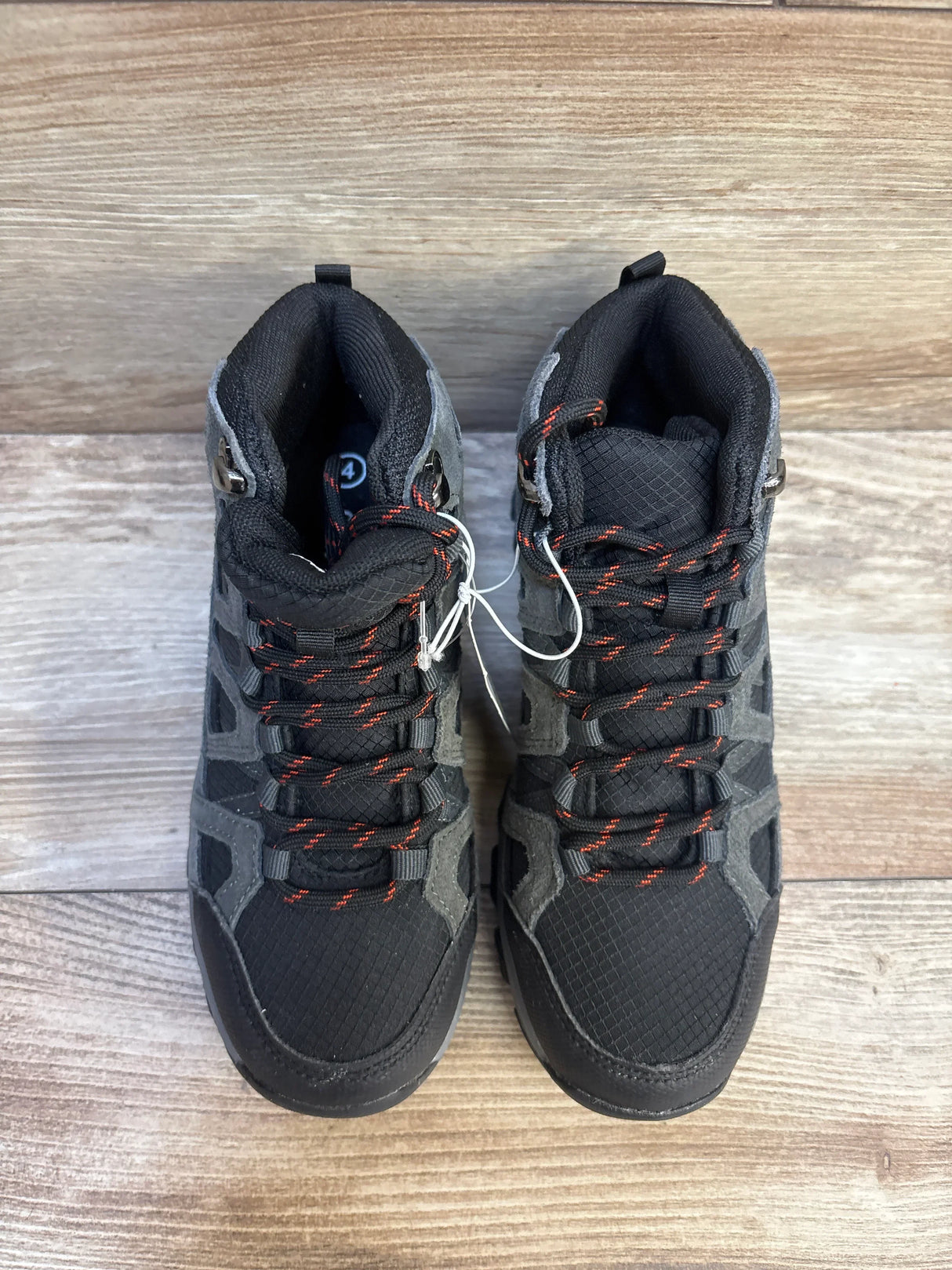 Kids black and gray hiking boots with red laces on wood floor