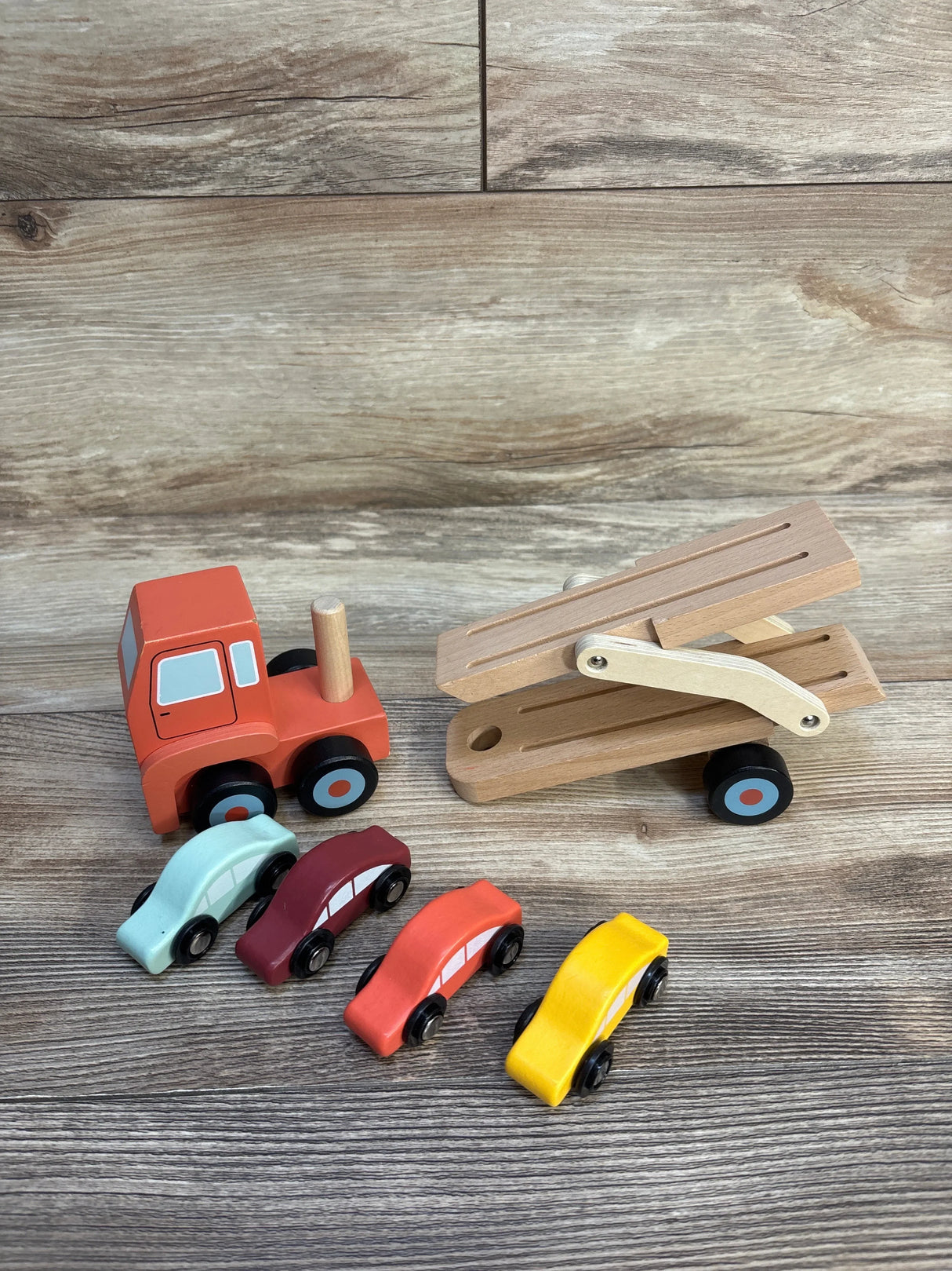 Wooden toy car carrier truck with four colorful wooden toy cars on wood background