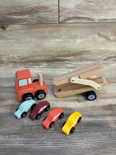 Wooden toy car carrier truck with four colorful wooden toy cars on wood background