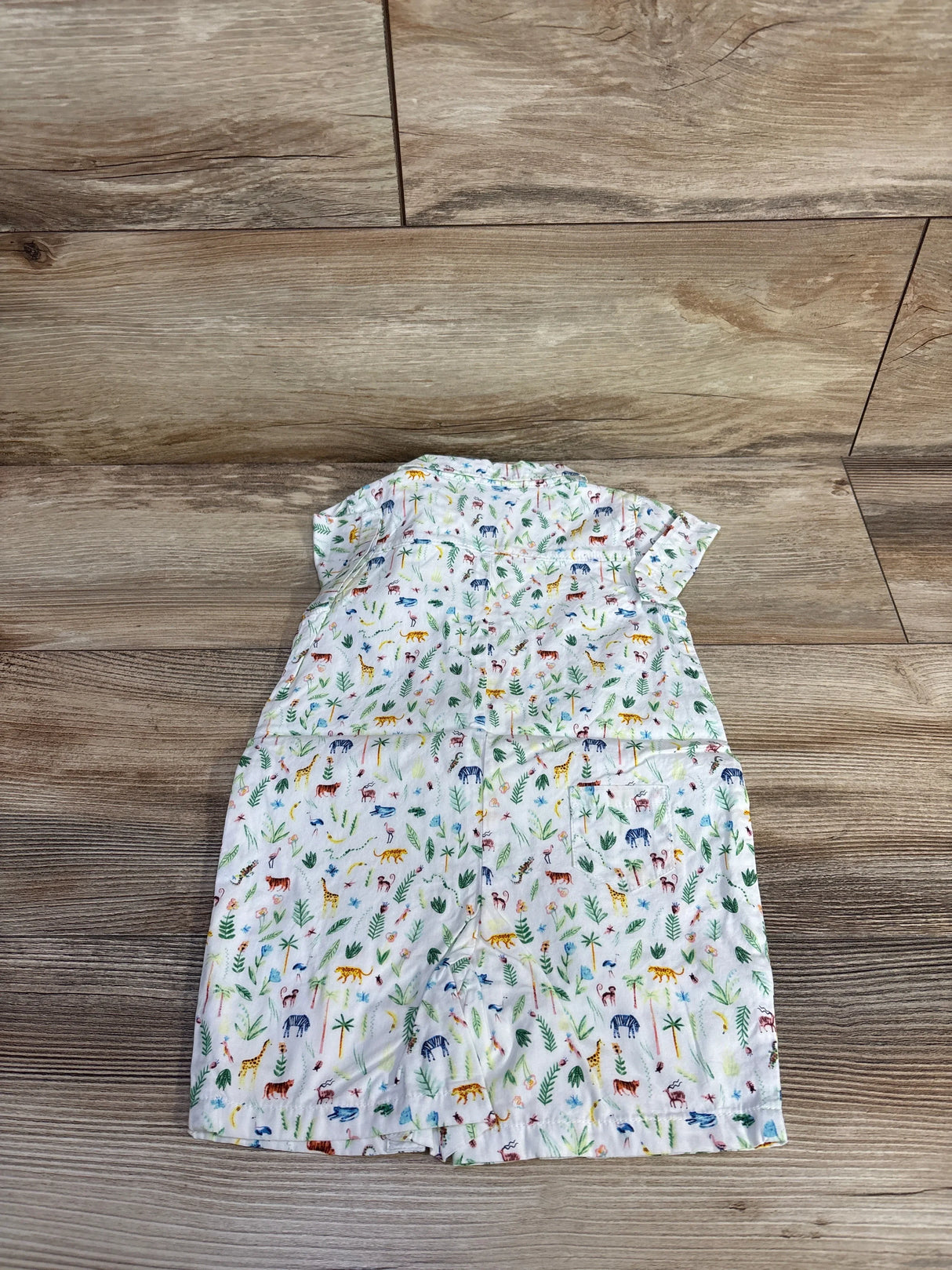 Back view of Janie & Jack white shortie romper showing multicolored jungle animal print and short sleeves on wood floor background